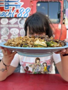 Guest holding a plated meal in front of a food truck at Food Trucks Heaven